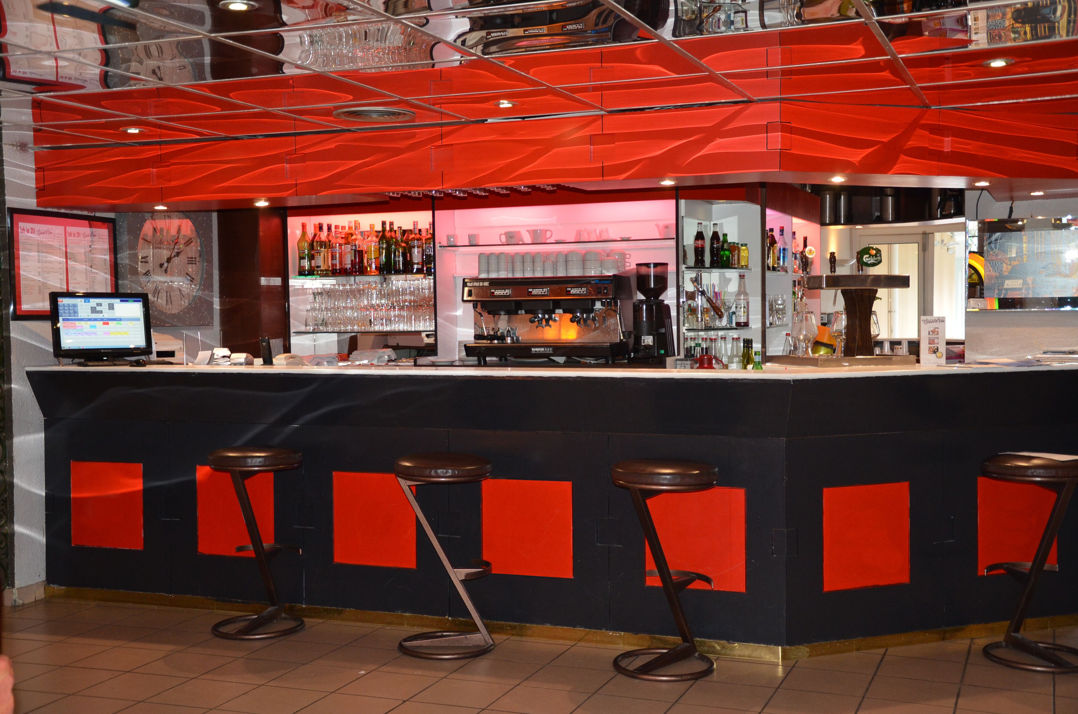 A bar area with a counter, stools, and a variety of bottles and glasses.