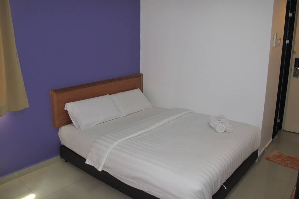 Ein Zimmer mit einem Einzelbett, einem hölzernen Kopfteil, weißer Bettwäsche und einem Handtuch auf dem Bett.