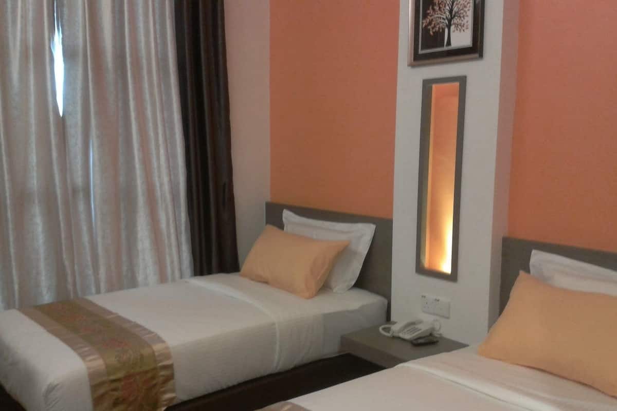 Ein Hotelzimmer mit zwei Betten, einem Nachttisch, einem Telefon und einem gerahmten Bild an der Wand.