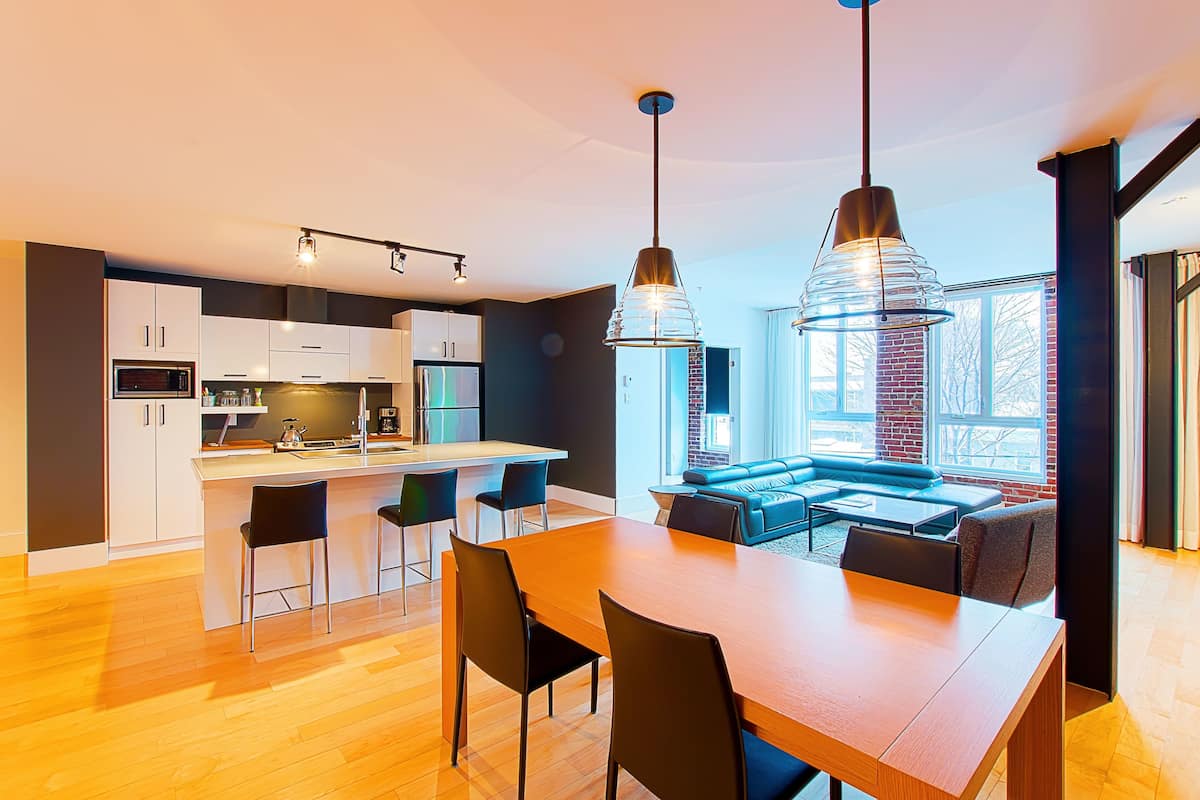 Una cocina moderna con una isla central, taburetes de bar e iluminación colgante.