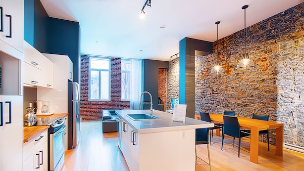 Een moderne keuken met witte kasten, een centraal eiland en een eethoek met een houten tafel en stoelen.