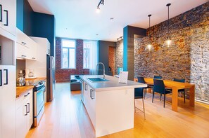 Eine moderne Küche mit weißen Schränken, einer zentralen Kochinsel und einem Essbereich mit Holztisch und Stühlen.