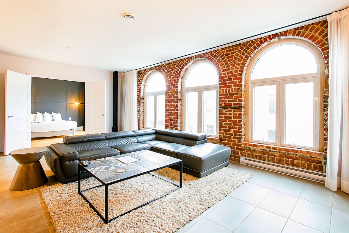 Una sala de estar moderna con un sofá modular, una mesita de centro y un ventanal con paredes de ladrillo en arco.