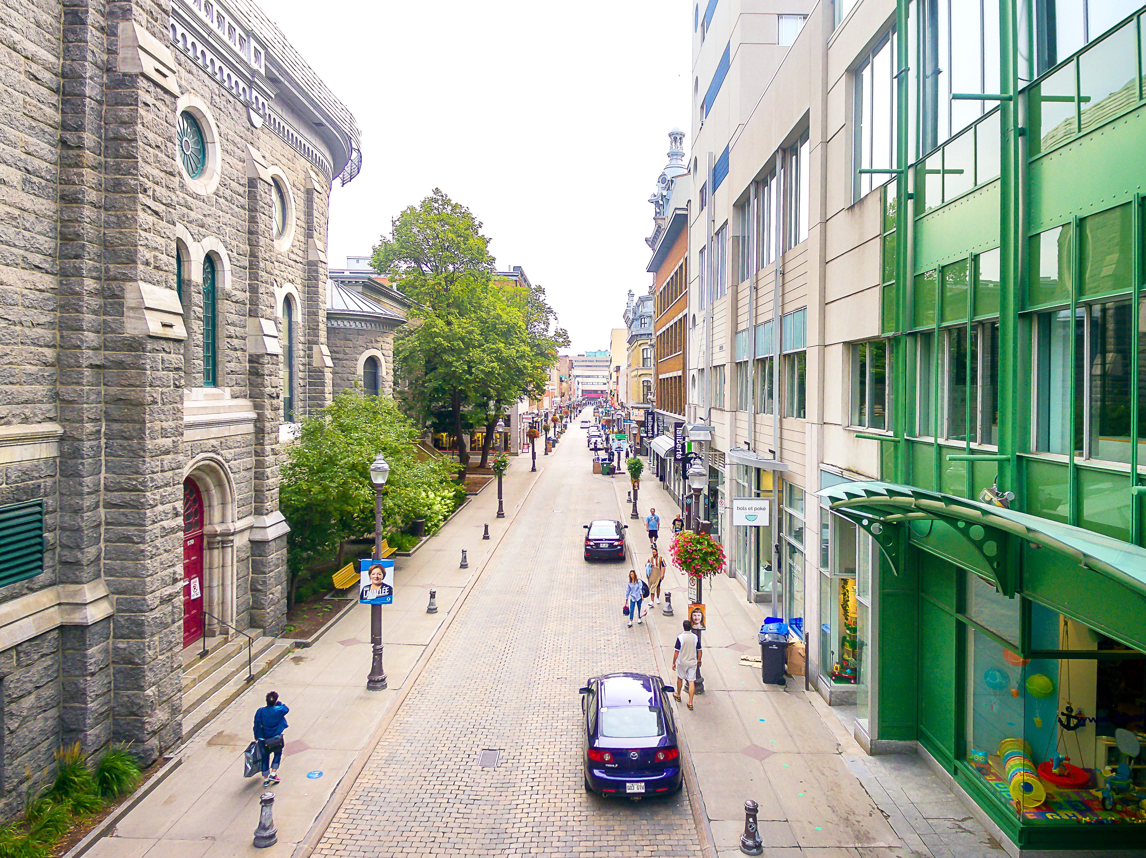 Eine gepflasterte Straße, gesäumt von historischen Steinbauten und modernen Geschäften mit Glasfassaden.
