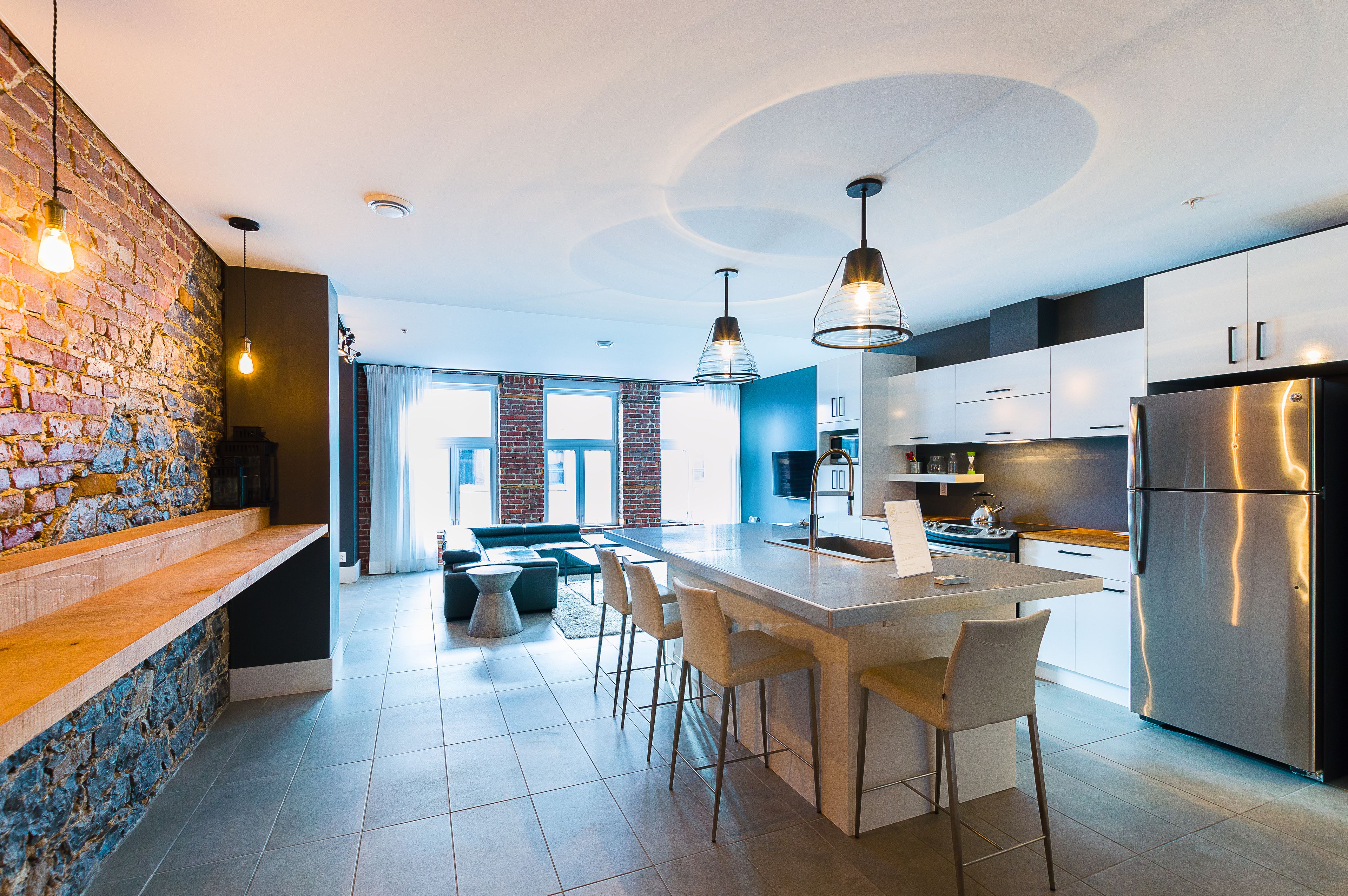 Une cuisine moderne dotée d’un îlot central, de tabourets de bar et d’appareils électroménagers en acier inoxydable.