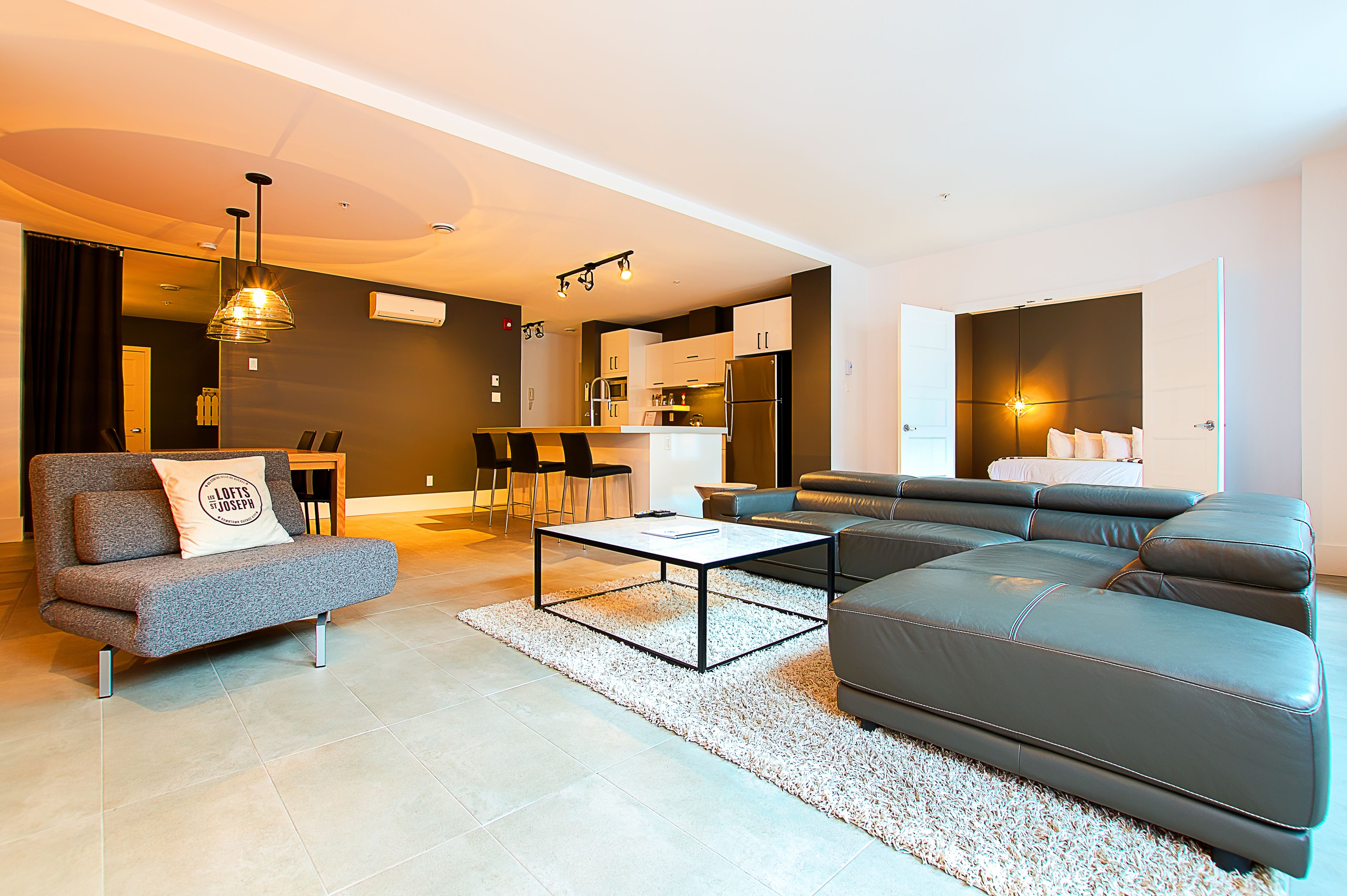 A modern living room with a sofa, a coffee table, and a dining area with chairs.