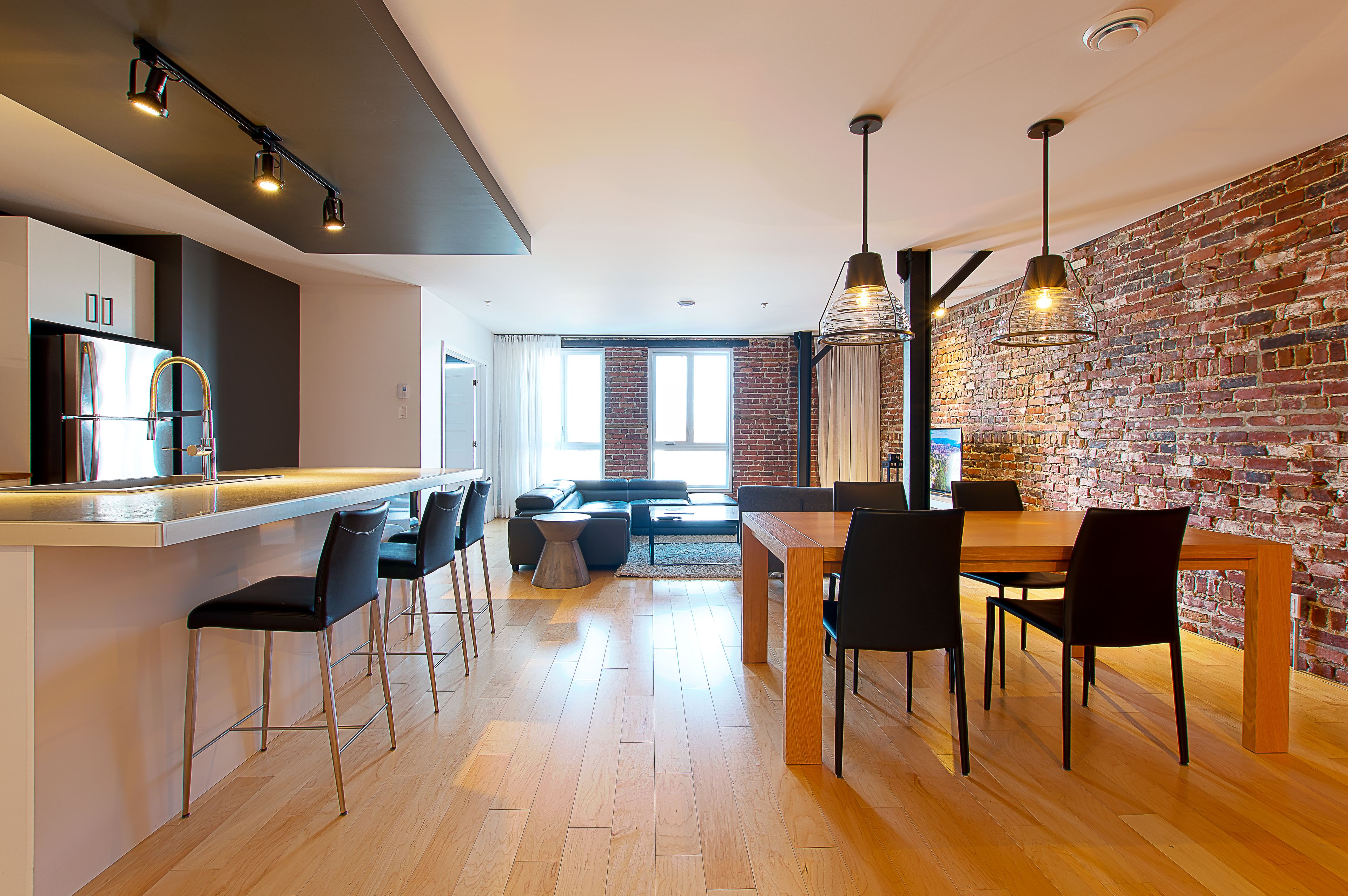 Una cocina moderna con barra, una mesa de comedor y sillas, y una pared de ladrillo.