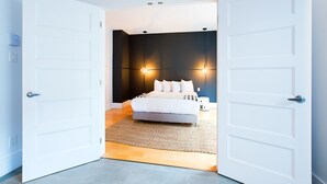 Een moderne slaapkamer met een bed, nachtkastjes en een wandlamp.
