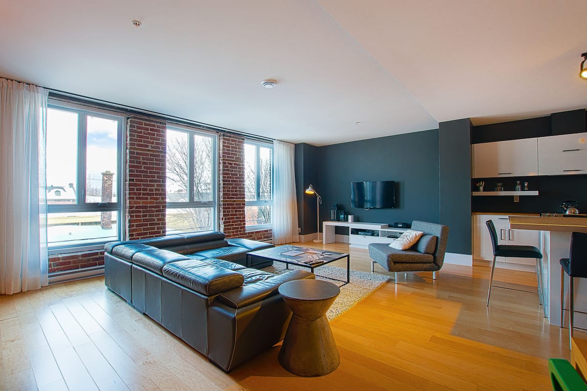 Una sala de estar moderna con un sofá grande, una mesa de centro y un televisor al fondo.
