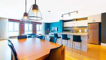 A modern kitchen with a central island, bar stools, and a dining table with chairs.