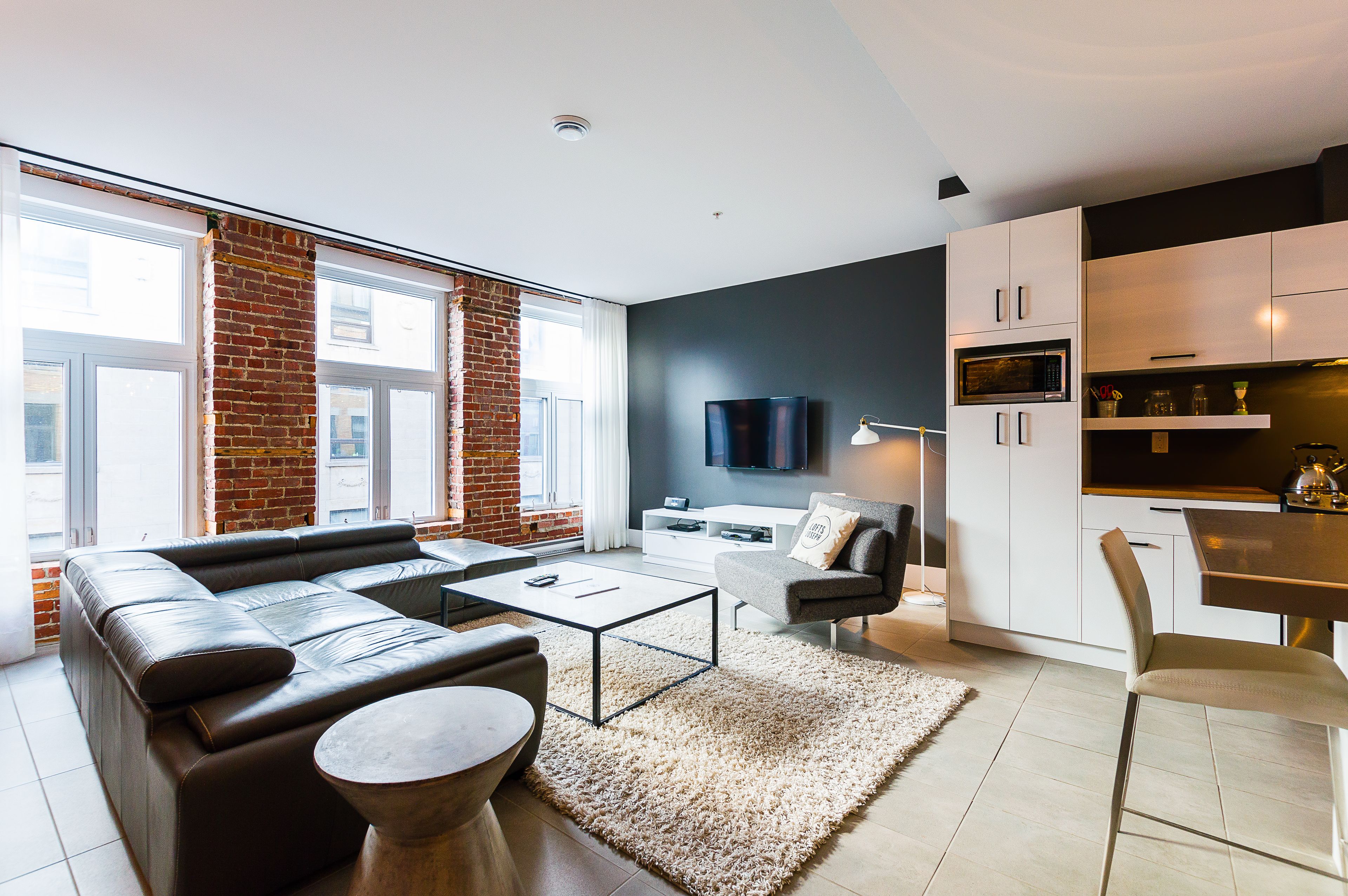Un salon moderne avec un canapé en cuir, une table basse et un téléviseur fixé au mur.