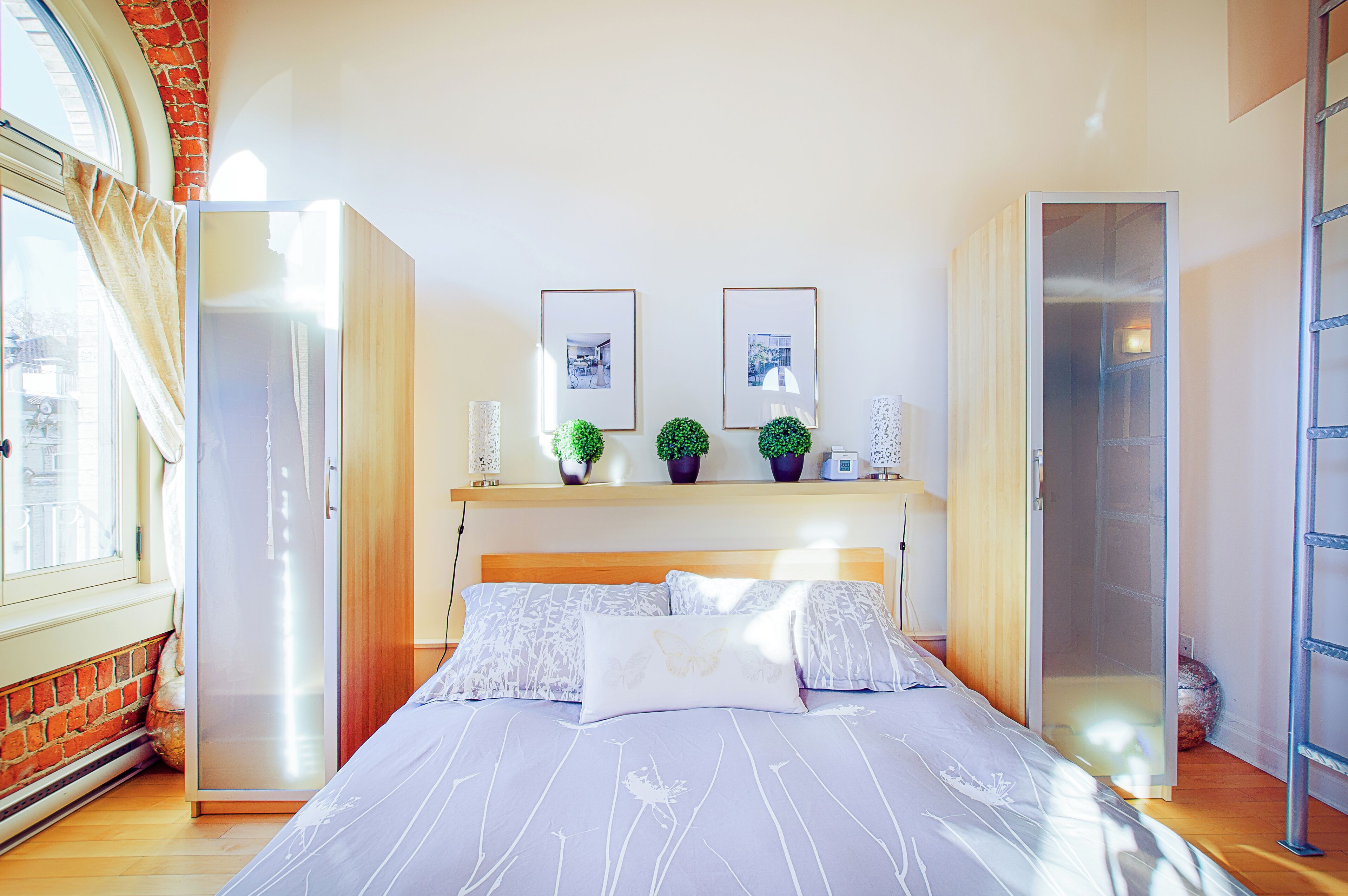 A bedroom with a bed, a wardrobe, a window, and a door.