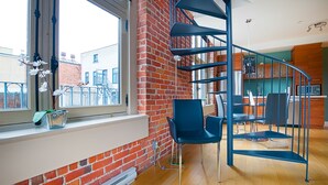 A modern interior with a brick wall, a spiral staircase, and a view of the city. - Les Lofts 1048 (Québec City)