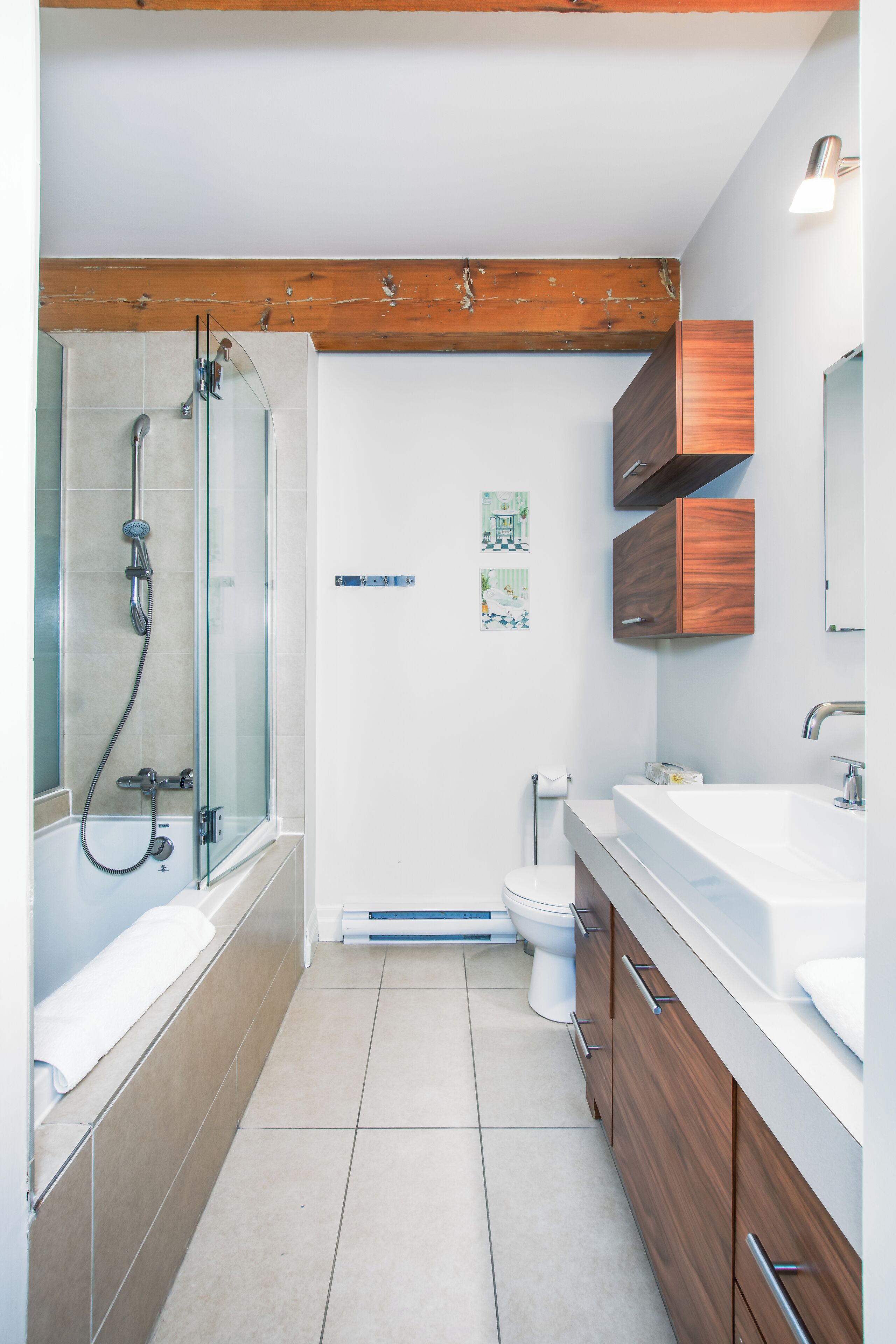 Un bagno moderno con doccia vetrata, un water bianco e mobili in legno.