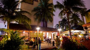 Een hotel met een bord waarop 'Paloma Hotel' staat en een restaurant met terras.
