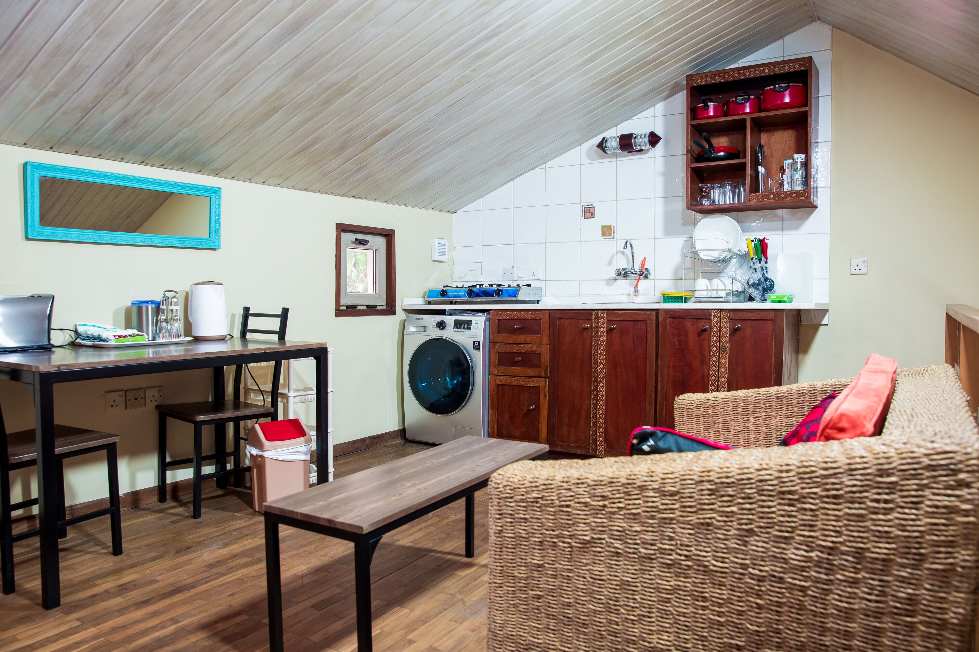 A compact kitchen with a washing machine, wooden cabinets, and a dining area with a table and chairs.