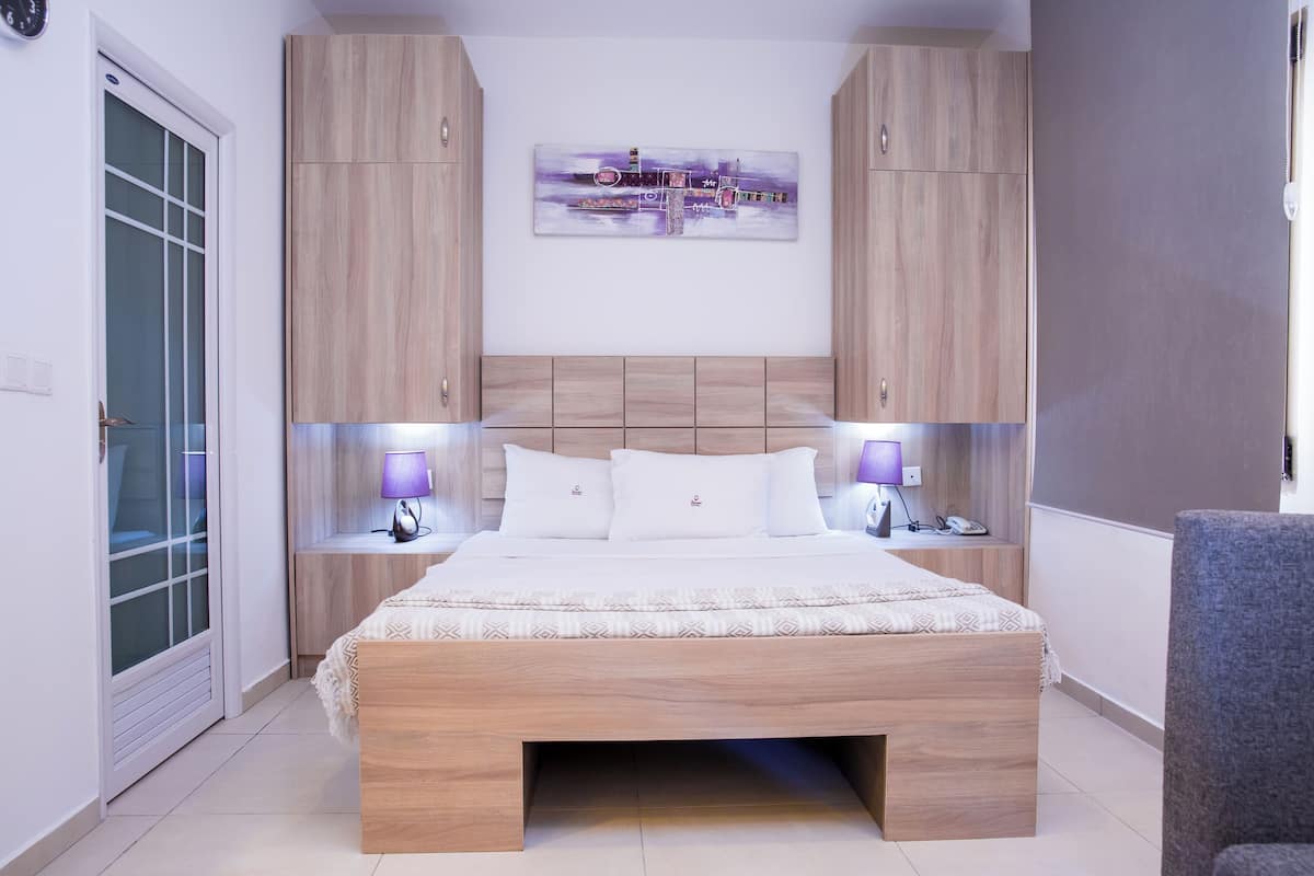 Une chambre moderne avec un lit en bois, des tables de chevet intégrées et une œuvre d’art accrochée au mur.