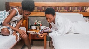 A bedroom with a bed, a nightstand, and a small table with a book and a cup.