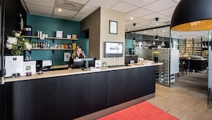 A modern reception area with a dark reception desk, a teal accent wall, and a red carpet. - Best Western Hotel Solna (Solna)