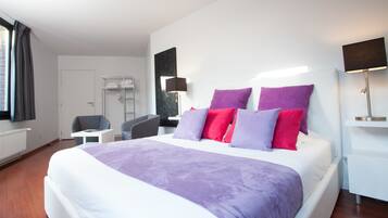 Een moderne hotelkamer met een groot bed, een nachtkastje, een stoel, een kledingkast en een raam met gordijnen.