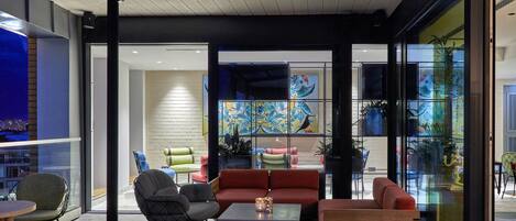 A modern interior with a seating area featuring sofas and chairs, a coffee table, and a view through large glass doors.