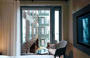 A hotel room with a balcony, a round table, and a chair.