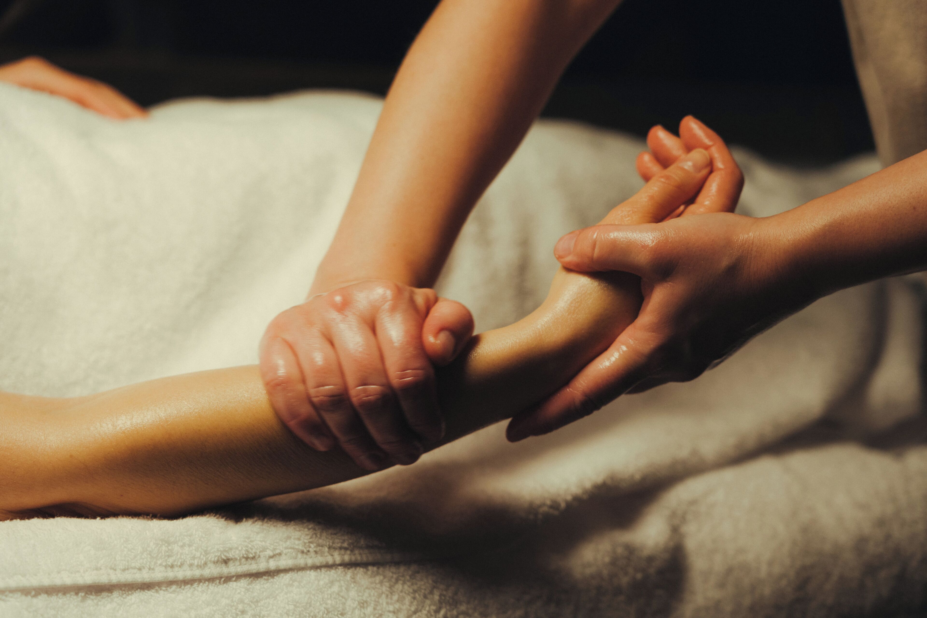 Un primo piano di mani che massaggiano il braccio di una persona.