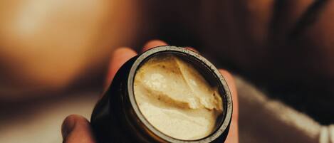 A hand holding a small container with a creamy substance.