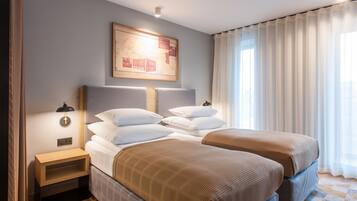 A hotel room with two beds, a nightstand, a wall-mounted lamp, and a large window with curtains.
