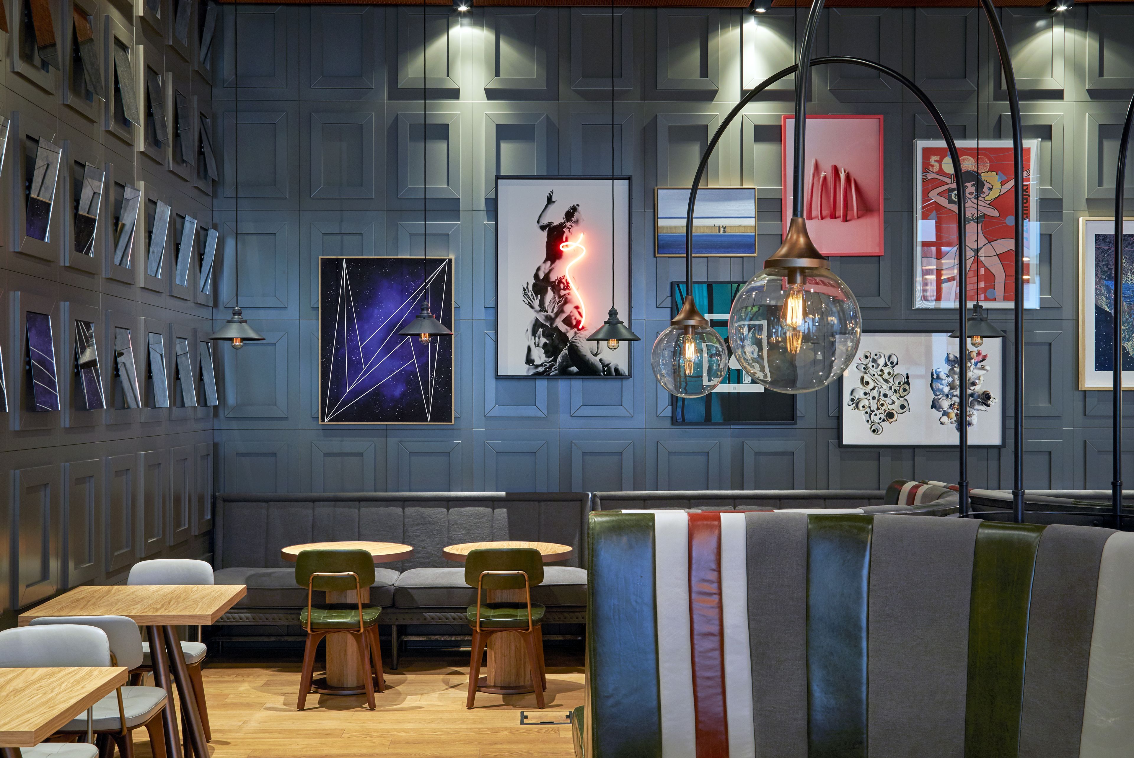A modern interior with a seating area, wooden tables, and a wall adorned with framed artwork.