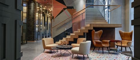 A modern lobby with a geometric patterned floor, a staircase, and contemporary seating arrangements.