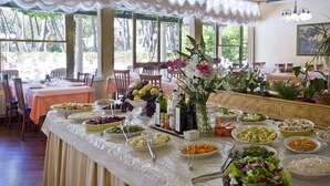 A dining area with a buffet setup, featuring various dishes and a decorative centerpiece. - Hotel Meeting (Cesenatico)