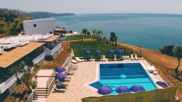 A resort with a swimming pool, lounge chairs, and umbrellas. - Samothraki Beach Apartments and Suites Hotel (Samothrace)