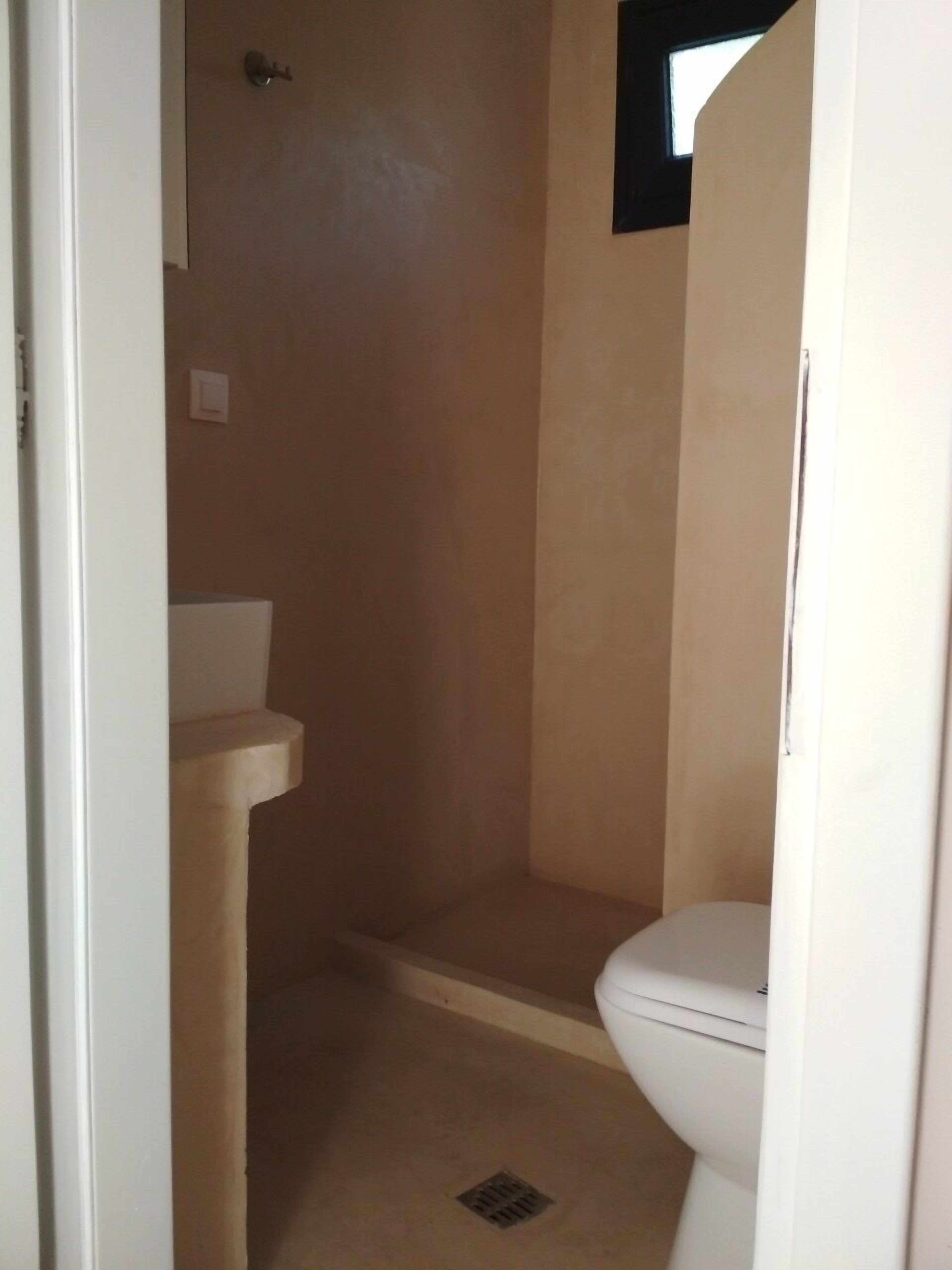 A small, enclosed bathroom with a toilet, a sink, and a shower stall.