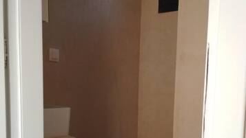A small, enclosed bathroom with a toilet, a sink, and a shower stall.