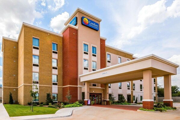 A Comfort Inn & Suites building with a brick facade, large windows, and a covered entrance.