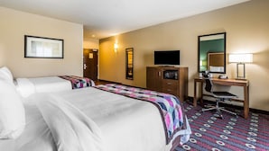 A hotel room with two beds, a desk, a chair, a television, and a patterned carpet.