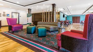 A modern lobby with a reception desk, colorful seating, and a decorative pillar.