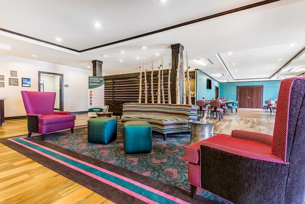 A modern lobby with a reception desk, colorful seating, and a decorative pillar.