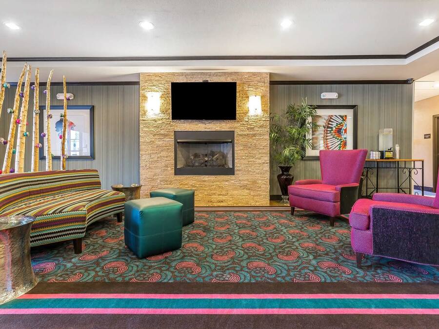 A modern living room with a stone fireplace, a flat-screen TV, and colorful seating.