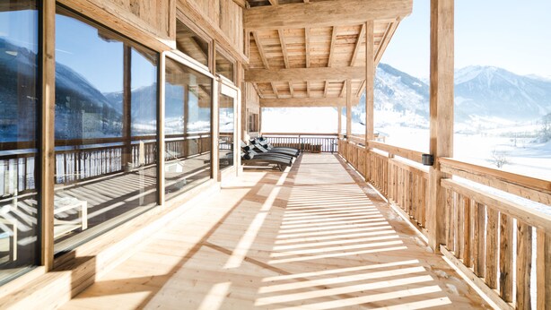 A wooden deck with a view of snow-covered mountains. - Feriendorf Ponyhof (Fusch an der Grossglocknerstrasse)