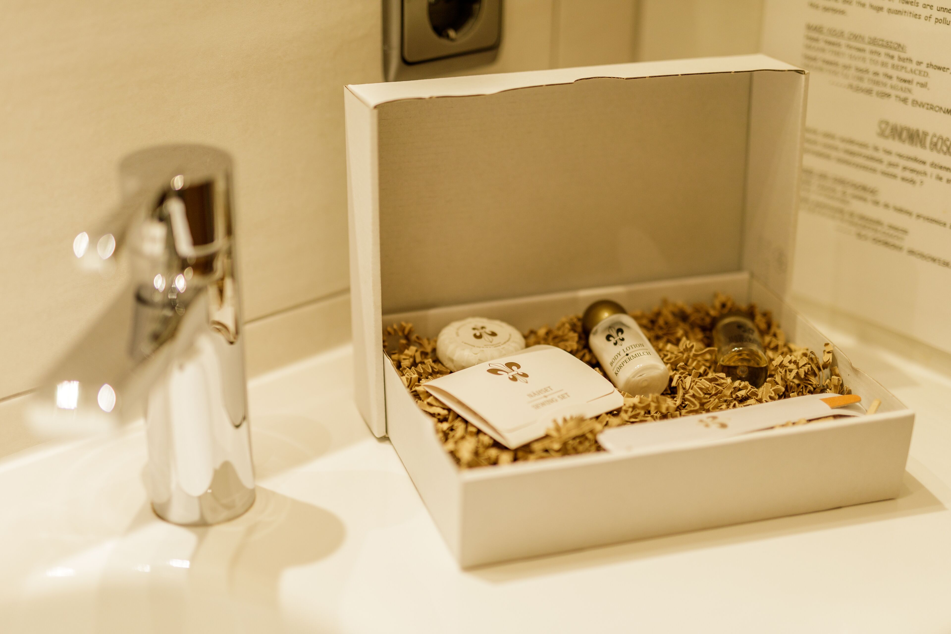 A bathroom sink with a white box containing toiletries and a bottle of shampoo.