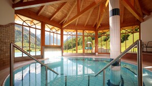 A swimming pool with a view of mountains, wooden beams, and a tiled floor. - Feriendorf Ponyhof (Fusch an der Grossglocknerstrasse)