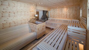 A wooden sauna room with benches and a hanging light fixture. - Feriendorf Ponyhof (Fusch an der Grossglocknerstrasse)