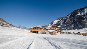 A large, multi-story chalet with a ski lift in the background, surrounded by snow-covered mountains. - Feriendorf Ponyhof (Fusch an der Grossglocknerstrasse)