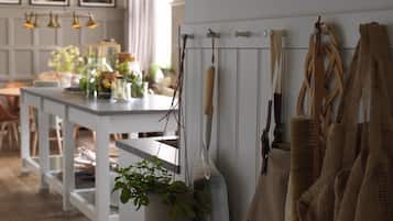 Une cuisine avec des plantes suspendues, une table blanche et un porte-ustensiles suspendu.