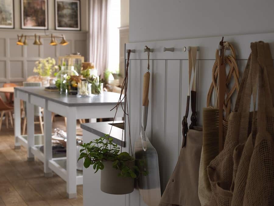Una cucina con piante pensili, un tavolo bianco e una rastrelliera sospesa per pentole.