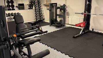 A gym with various exercise equipment, including dumbbells, a bench press, and a squat rack.