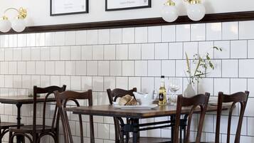 A dining area with a long table, wooden chairs, and a tiled backsplash.
