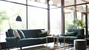 Una sala moderna con un sofá verde, una mesita y un suelo a cuadros.